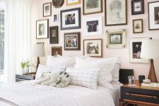 a beautiful bedroom with a blush accent wall done with a vintage gallery wall, a blakc bed with neutral bedding and black nightstands