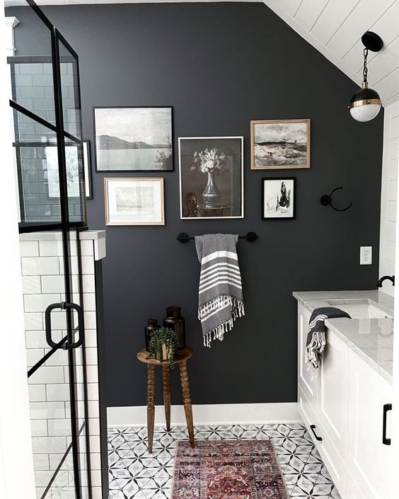 a black and white bathroom with a black accent wall, a monochromatic gallery wall, white furniture and a shower space done with white subway tiles