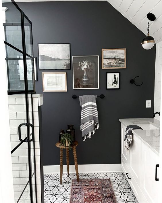 a black and white bathroom with a black accent wall, a monochromatic gallery wall, white furniture and a shower space done with white subway tiles