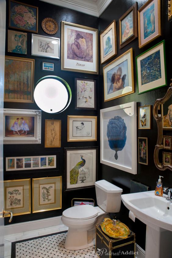 a black powder room with a round window, vintage artwork all over the space, white appliances and lights here and there
