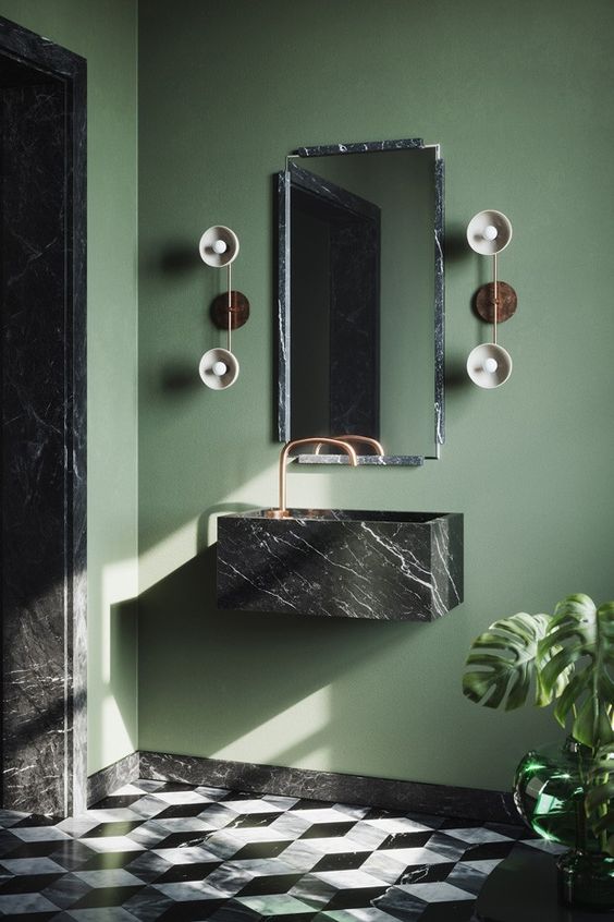 a bright mudroom with green walls, a black marble floating sink, a mirror in a matching frame and catchy sconces