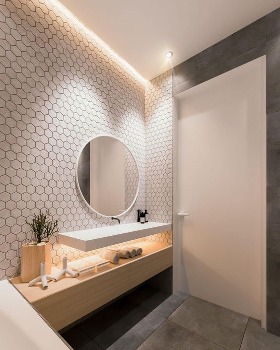 a catchy contemporary bathroom with a white hex tile wall, a floating sink and a sleek vanity, a bathtub and a round mirror