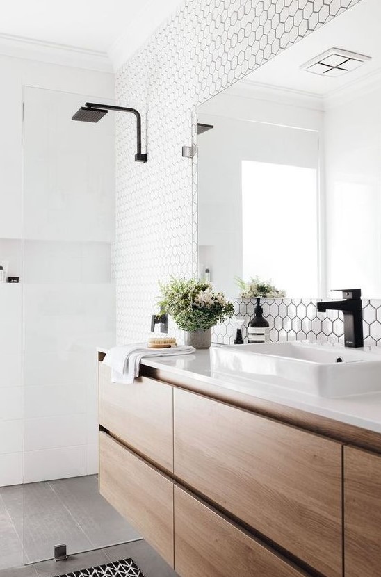 a chic Scandinavian bathroom with white hex and square tiles, a floating wooden vanity and black touches here and there