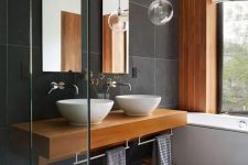 a contemporary bathroom with large scale dark grey tiles, a wooden accent wall, a floating timber vanity and mats