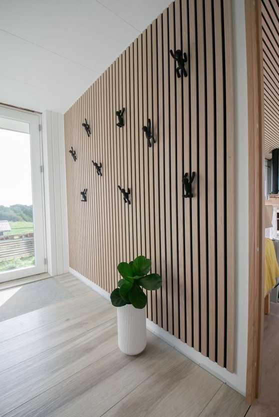 a contemporary entryway with a wood slat with decor and a potted plant is a lovely and cool space filled with light