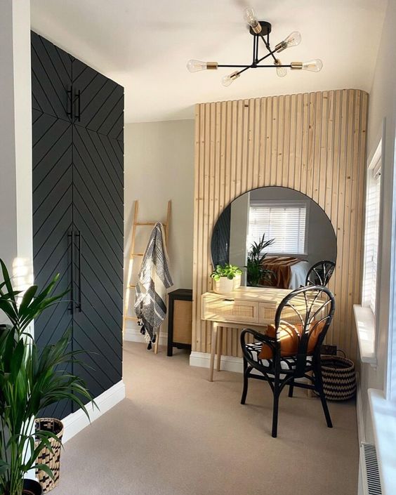 a cool entryway with a built-in wardrobe, a wood slat accent wall, a round mirror, a cane console table and a black chair