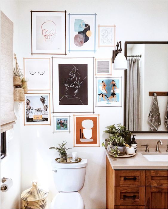 a farmhouse bathroom in white, with a stained vanity and white appliances, a mirror, a colorful gallery wall for an accent