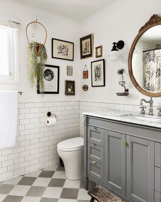 a farmhouse bathroom with white subway tiles, a grey vanity, white appliances, a vintage gallery wall and greenery, a mirror in a wooden frame