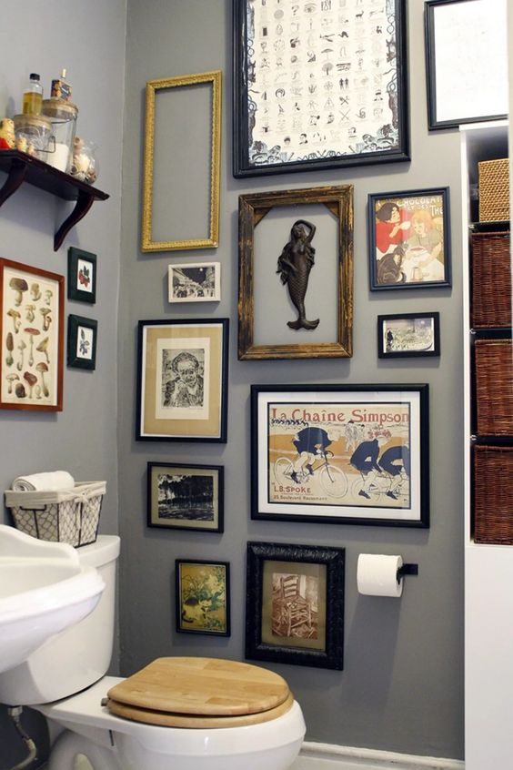 a grey bathroom with a catchy vintage gallery wall, white appliances and baskets for storage is a lovely space