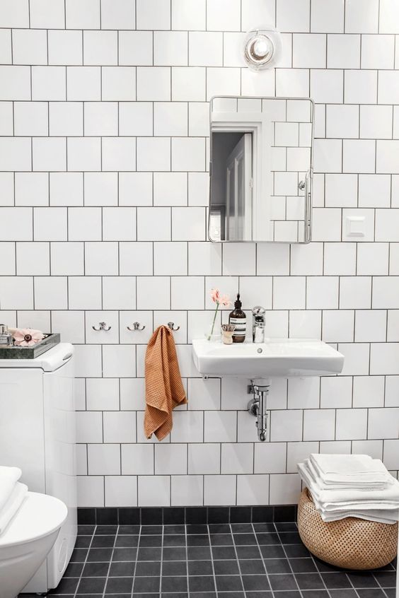 a lovely modern Scandi bathroom with white and black square tiles, white appliances including a floating sink and a cool mirror