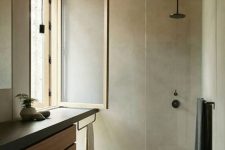 a minimalist bathroom clad with concrete, a floating wood and concrete vanity, a window and a wooden floor and ceiling