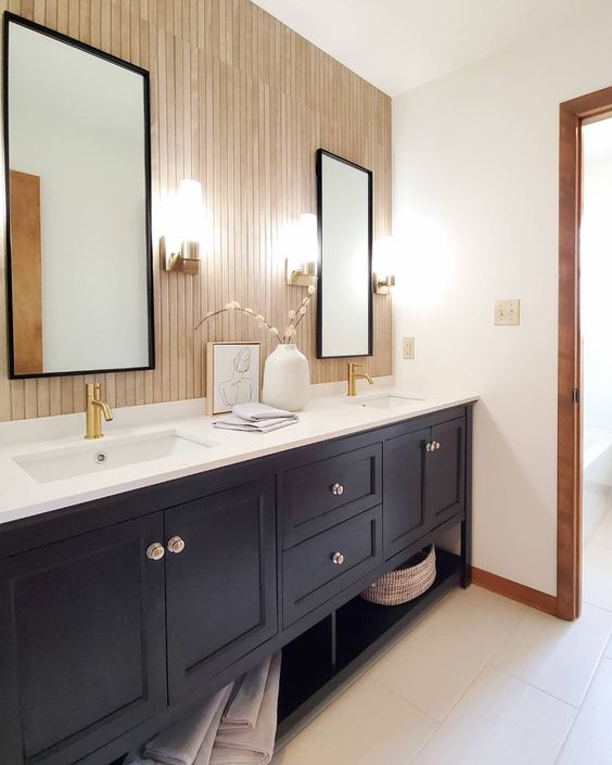 a modern farmhouse bathroom with a wood slat accent wall, a navy double vanity, two mirrors and some decor plus sconces