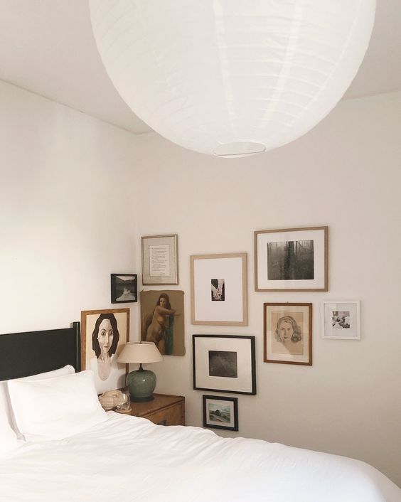 a neutral bedroom with a vintage feel, a black bed with white bedding, a vintage inspired corner gallery wall is amazing