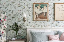 a pastel vintage bedroom with blue floral wallpaper, a neutral bed with pastel bedding, neutral nightstands, a vintage gallery wall and a floral dress