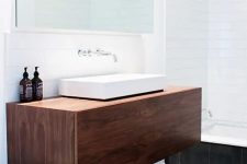 a rich-stained floating timber vanity with a square sink and some bottles will provide you with storage space and won’t take any floor space