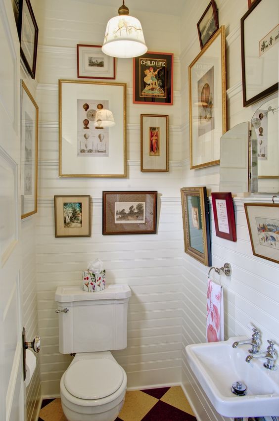 a small neutral mudroom with planked walls, white appliances, vintage gallery walls and a pendant lamp and printed towels