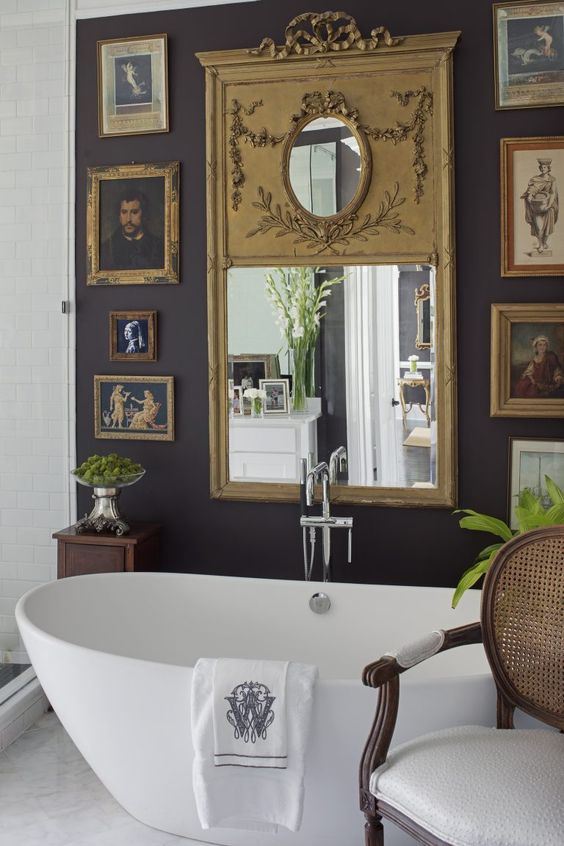 a vintage bathroom with a black accent wall and a chic vintage gallery wall, an oval tub and a mirror is a refined space