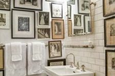 a vintage neutral bathroom with a gallery wall that takes two walls, neutral free-standing appliances, a mirror and lights