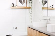 a welcoming Nordic bathroom with white hex and large scale tiles, a double vanity, round sinks and some art and greenery