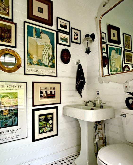 a white farmhouse bathroom with a vintage gallery wlal, a mirror, white appliances and black towels is a chic space