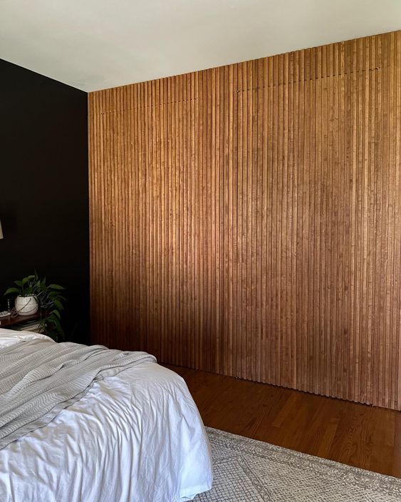 a wood slat wall hiding a closet is a cool idea, it looks seamless and adds coziness to the bedroom making it cooler and warmer