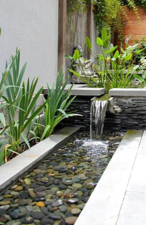 a chic modern waterfall going from a bowl with plants into a bowl with feathers and grasses around is a cool idea