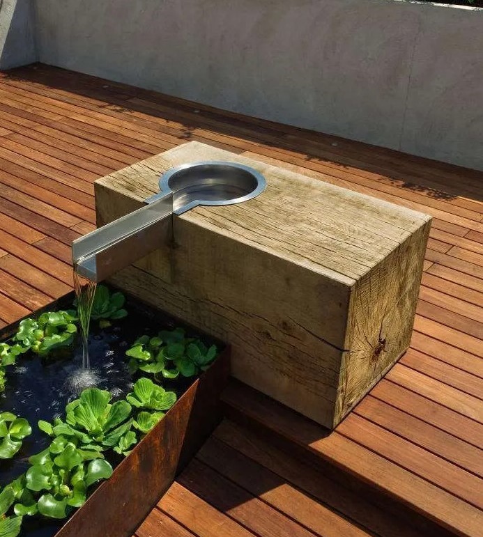 a Corten steel water feature built into a wooden deck is design to develop patina over time and look a bit more vintage