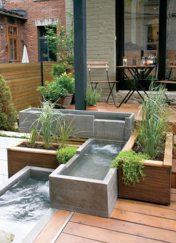 a modern outdoor space clad with a wooden deck, with a modern waterfall of concrete boxes and greenery is a cool and edgy nook