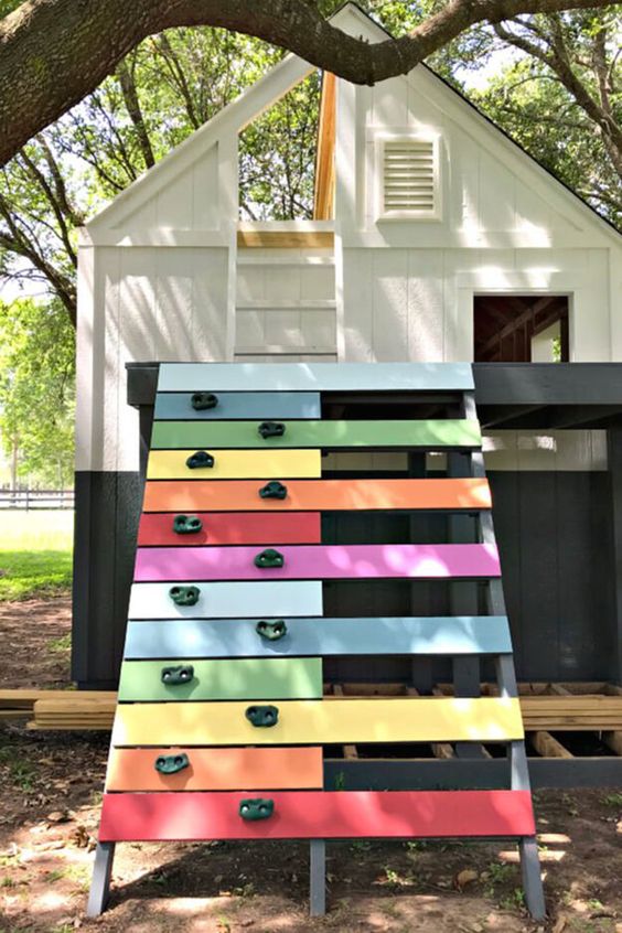 a color block playhouse with a ladder to the attic and a colorful ladder with a climbing wall is a veyr fun and cool idea
