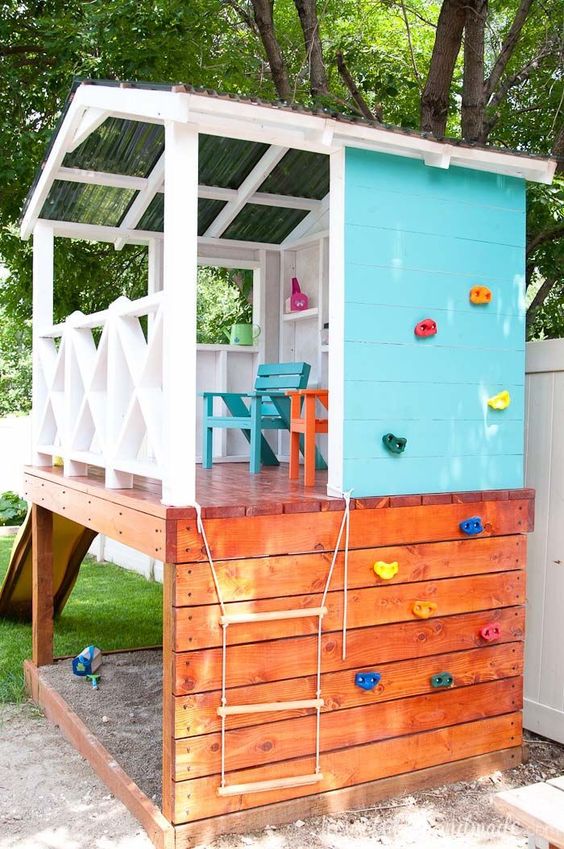 a colorful outdoor kids' playhouse with a climbing wall, a rope ladder and colorful wooden furniture plus a slide a colorful outdoor kids' playhouse with a climbing wall, a rope ladder and colorful wooden furniture plus a slide