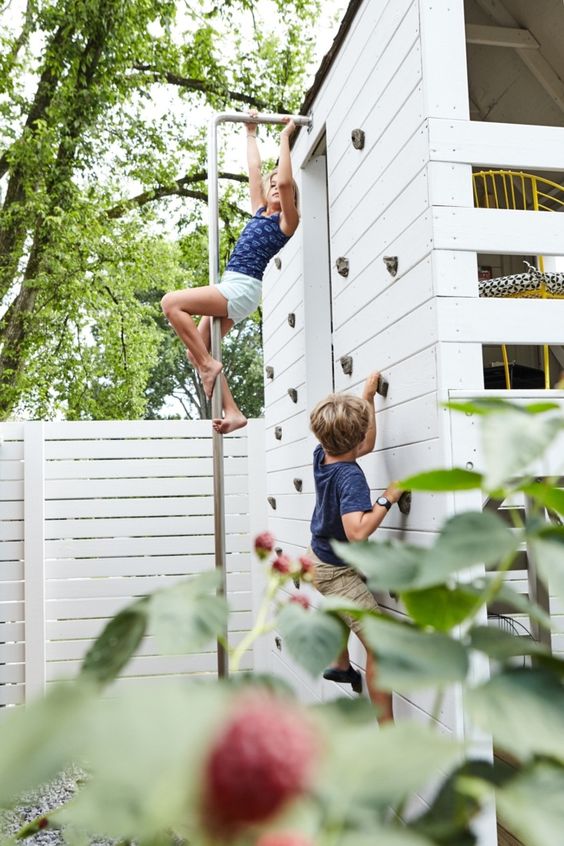 a kids' house in the garden with a climbing wall to let kids play and have fun here in many ways