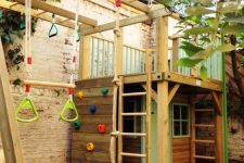 13 a kids’ playground with a wooden house with ladders and a platform on top, with a climbing wall, some rope for climbing and other stuff