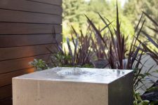 15 a minimalist stone slab fountain surrounded with black pebbles is a bold and cool solution for a contemporary space