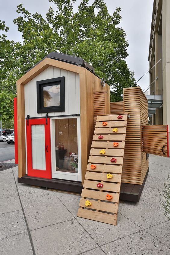 a lovely kids' house with a sliding door, an attic and a climbing wall instead of a usual ladder is a creative way to make your kids move more