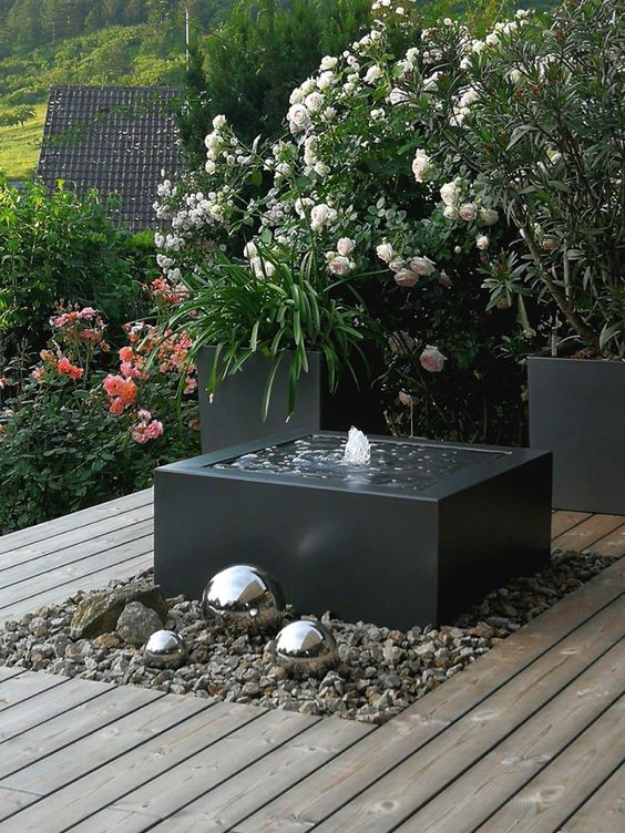 a modern interpretation of a fountain, with a black bow, pebbles around and some silver spheres next to it is a cool idea