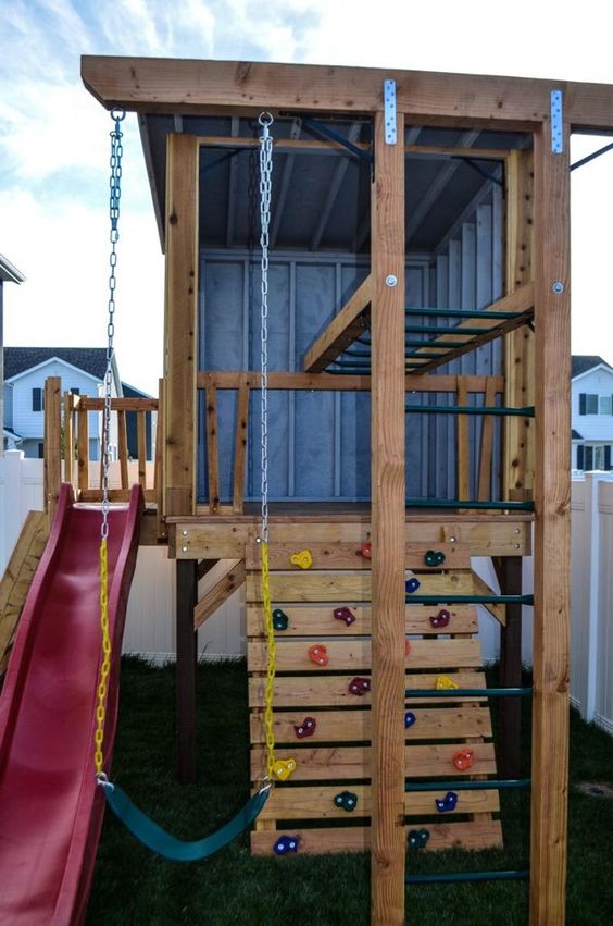 an outdoor mini house with ladders, a climbing wall, a red slide and a green swing is a lovely idea for kids' activities