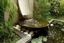 25 a stylish modern fountain with a wave going down and a metal bowl plus an additional pond with rocks and pebbles