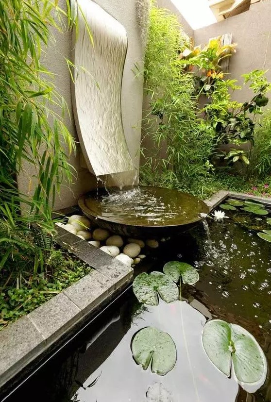 a stylish modern fountain with a wave going down and a metal bowl plus an additional pond with rocks and pebbles