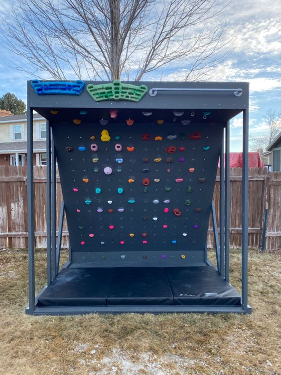 a cool and smartly organized climbing wall with a roof and a soft pad under the wall to make sure your kids won't hurt themselves
