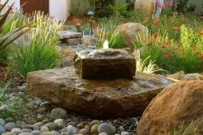 27 a unique and bold stone slab fountain, landscaping and pebbles around create a gorgeous look in the garden