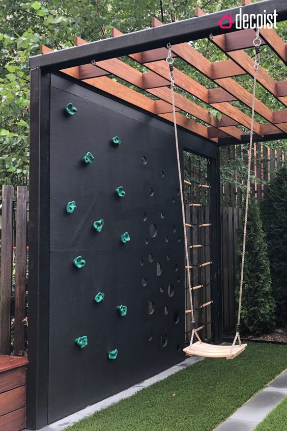 a kids' playground with a swing, a climbing wall and a wall with cutout circles will let your kids be active and have fun a kids' playground with a swing, a climbing wall and a wall with cutout circles will let your kids be active and have fun