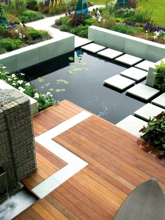 a modern outdoor space with a wooden deck and stone pavements, with water plants and a water garden is a lovely and chic space