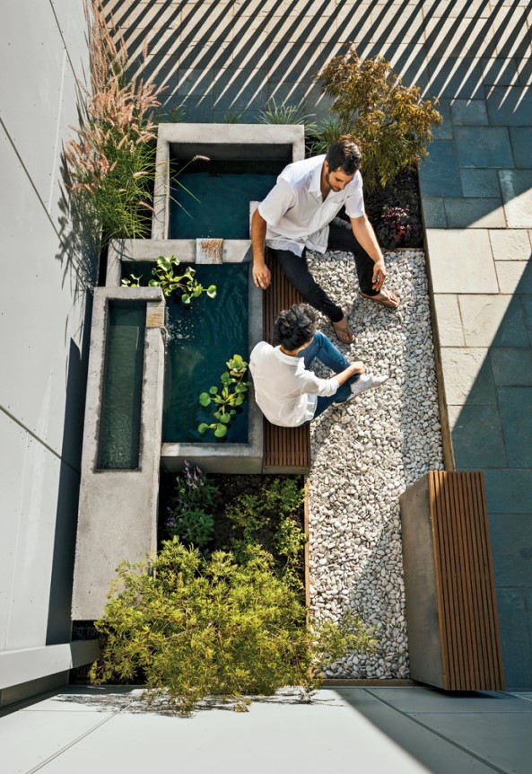 a three-part concrete and metal fountain with water hyacinths, a built-in bench and some pebbles are a lovely idea for a micro modern outdoor space