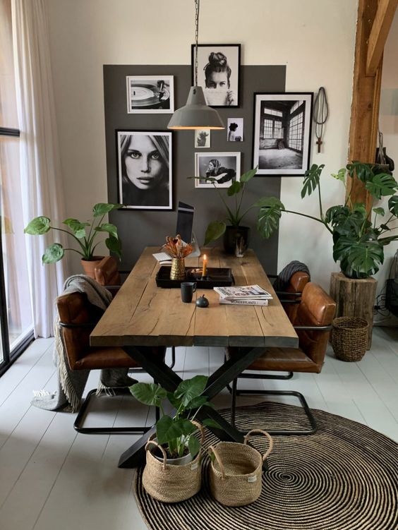 a Nordic dining room with a planked table and leather chairs, a rug, some baskets and a black and white gallery wall