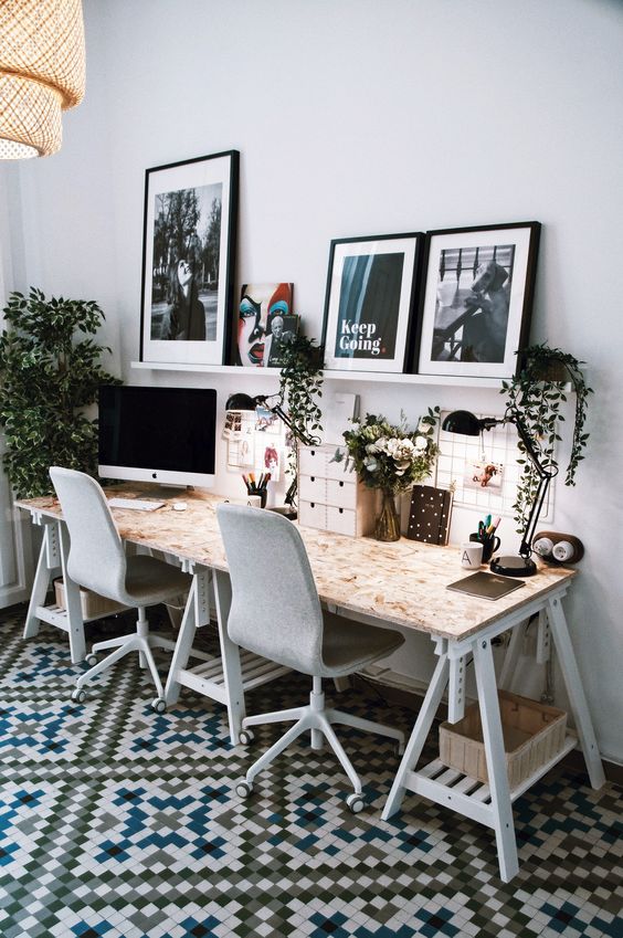 a Scandi home office with a shared trestle desk, grey chairs, a ledge gallry wall and a woven pendant lamp plus greenery