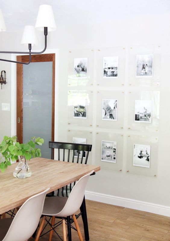 a Scandinavian dining space with a light-stained table and mismatching chairs, a floating gallery wall and a chandelier