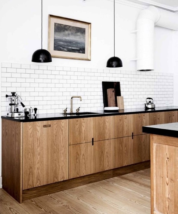 a Scandinavian kitchen with sleek stained cabinets, black stone countertops, a white subway tile backsplash, black pendant lamps
