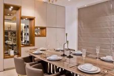 a beautiful contemporary dining room with built-in and pendant lamps, with a long table and taupe chairs, a storage unit with mirrors