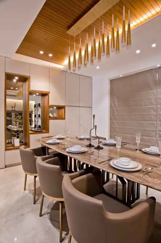 a beautiful contemporary dining room with built in and pendant lamps, with a long table and taupe chairs, a storage unit with mirrors