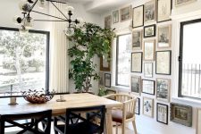 a beautiful dining room with a light-stained table and mismatching chairs, a chic chandlier and a monochromatic gallery wall